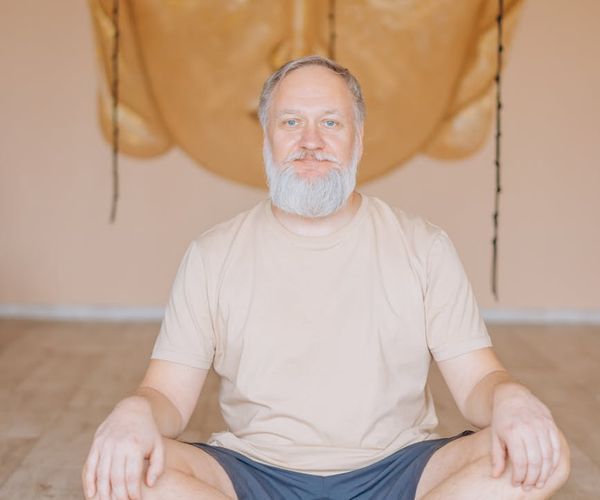 Person meditating peacefully on a yoga mat in a sunlit room.